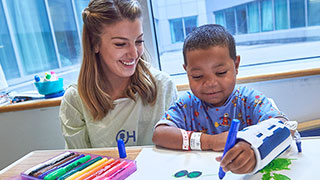 Child life specialist sitting with a child who is drawing