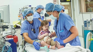 Anesthesia team situating infant in OR