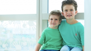 Young cancer patient sitting with brother in window smiling