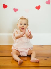 Baby on floor smiling with hearts around her