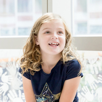 Blonde freckled girl sitting by the window and smiling