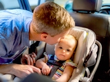 Father placing baby in car seat