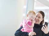 Mother holding infant and looking at phone