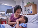 Mother comforting her daughter in her hospital bed