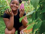 Young girl with freshly harvested vegetables in local garden