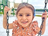 Lilliana smiling while riding a swing