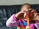 Child using inhaler with help of adult