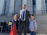 Father standing outside a courthouse with his children