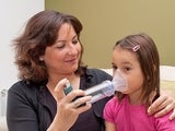 Mother helping daughter with inhaler