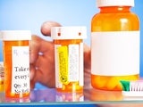 Hand reaching into medicine cabinet with pill bottles