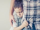 Young boy clinging to parent's leg