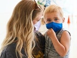 Mom holding son, both in masks