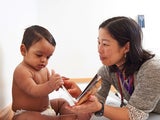 Elena Huang, M.D., a pediatrician at the Nicholas and Athena Karabots Pediatric Care Center, shares a book with Waldis, 8 months, as part of CHOP’s Reach Out and Read program.