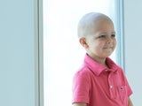 Young boy cancer patient sitting in hospital window smiling