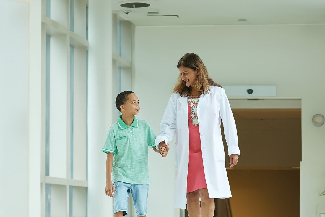 Physician walking down a hallway with her patient