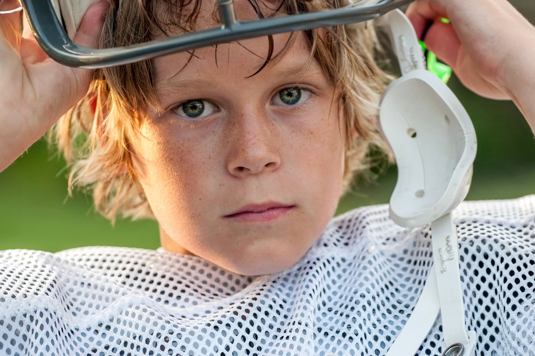 Young Boy taking his football helmet off looking concerned