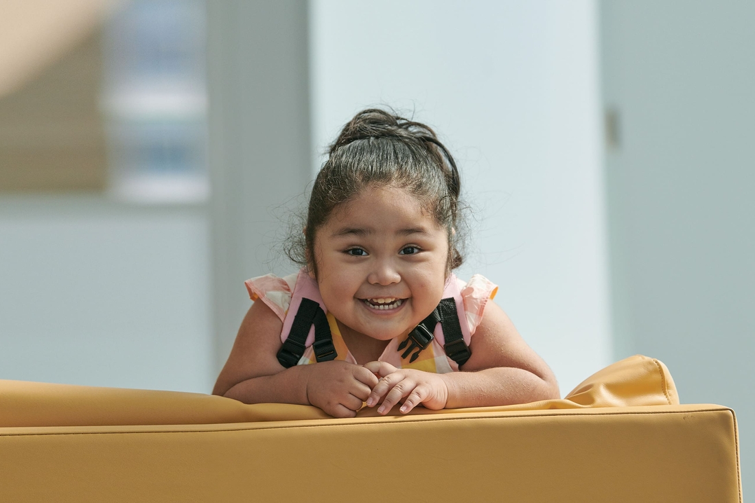 Young girl leaning over chair smiling