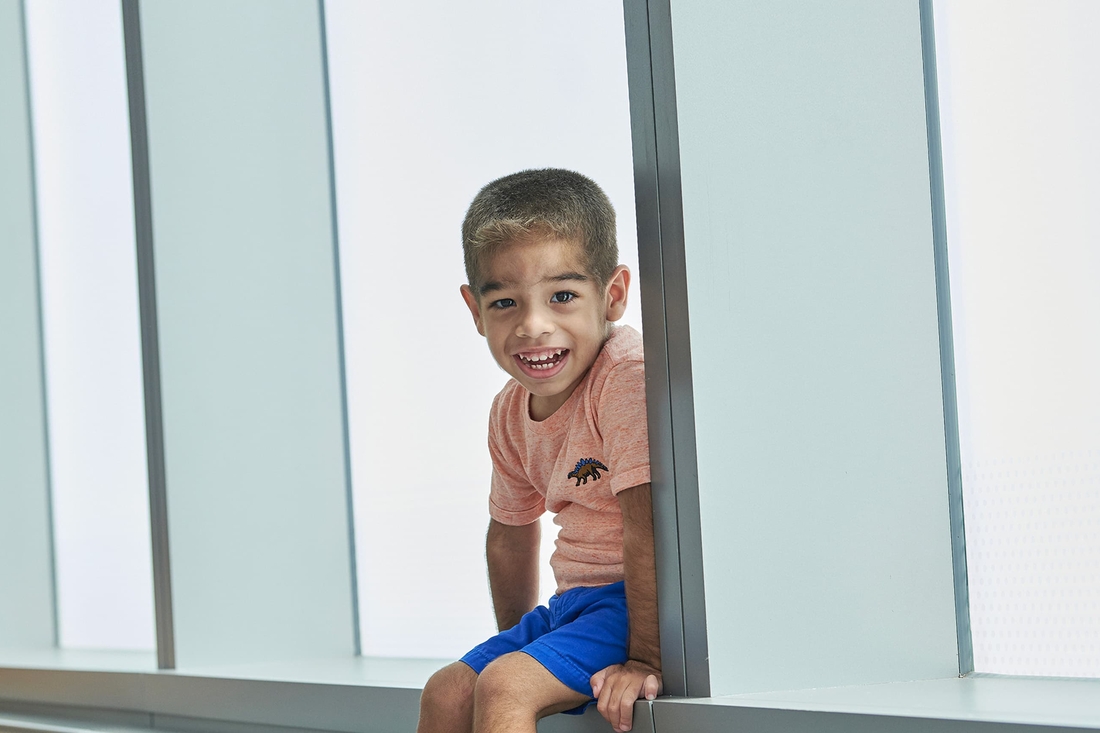 Young boy sitting on window ledge smiling