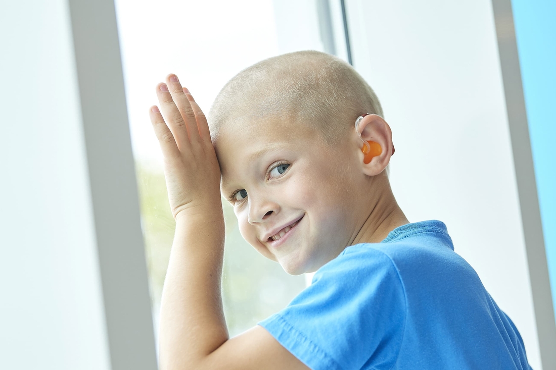 Smiling boy with a blue t-shirt wearing hearing aid