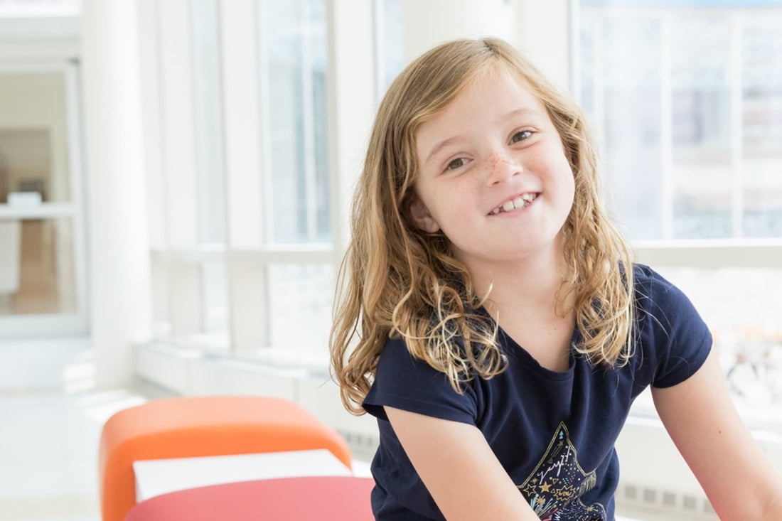 Smiling blonde girl with freckles wearing a dark blue t-shirt