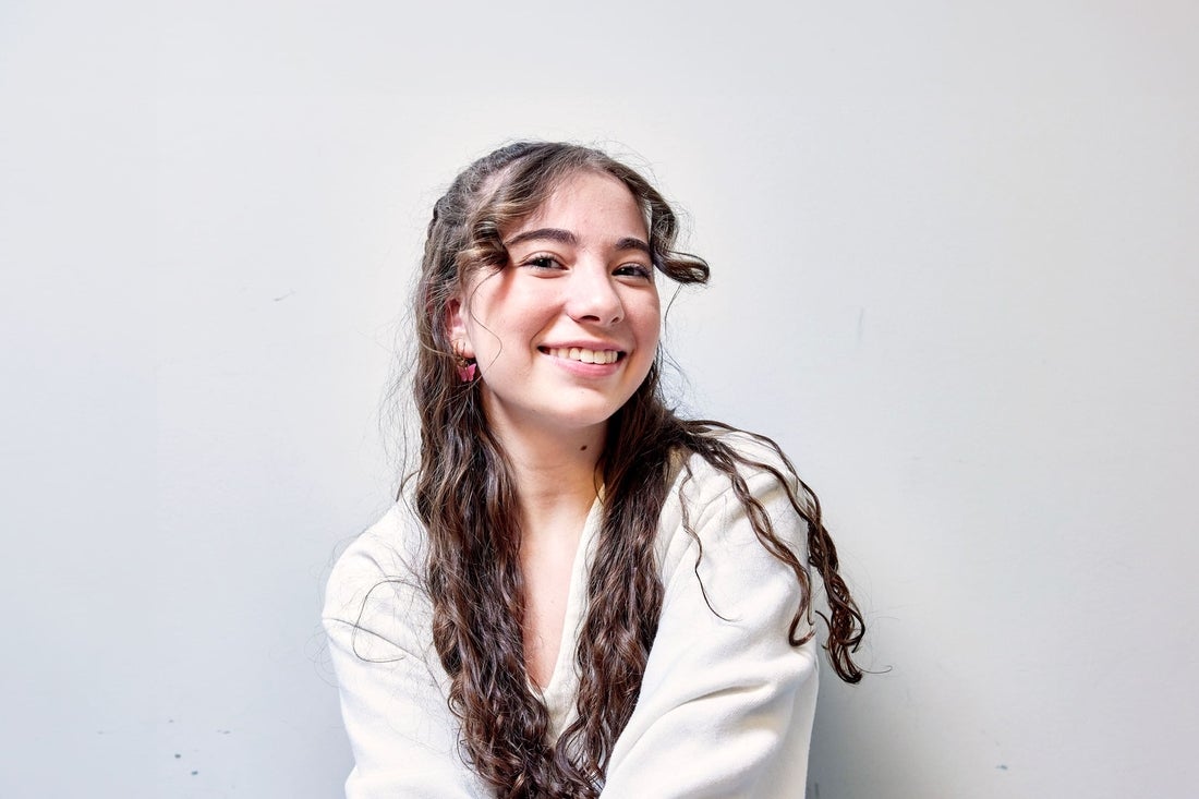 Happy teenage girl with long brown hair on grey background