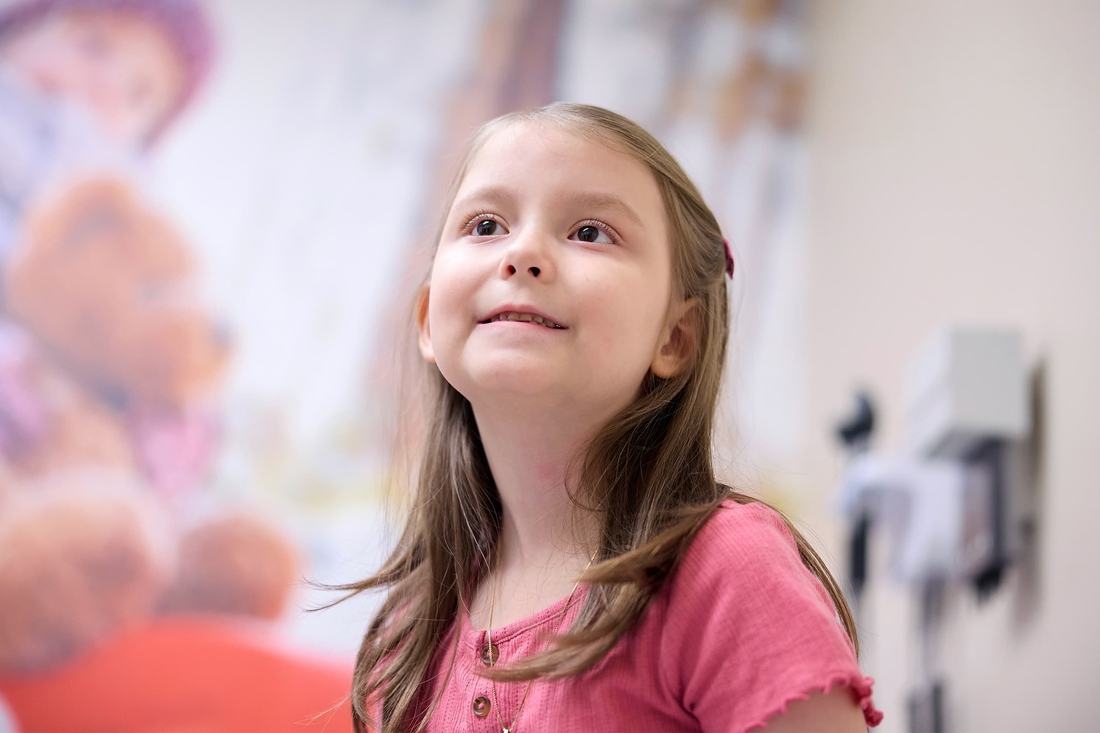 Young girl smiling and wearing a pink shirt.