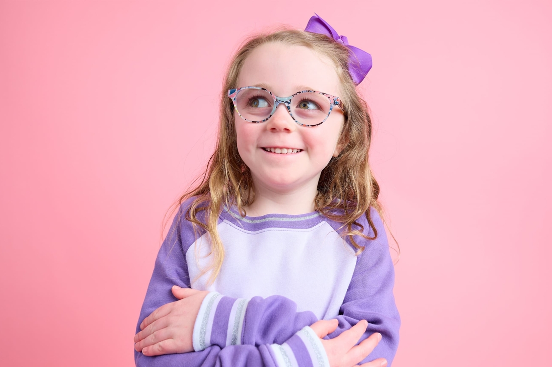 Sweet looking girl with purple bow in hair and fun glasses.