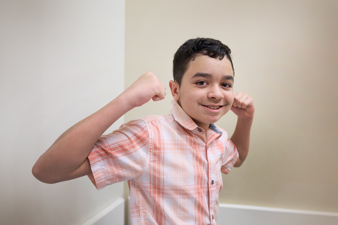 Tween boy flexing muscles looking strong sitting in Neurologist doctor office.