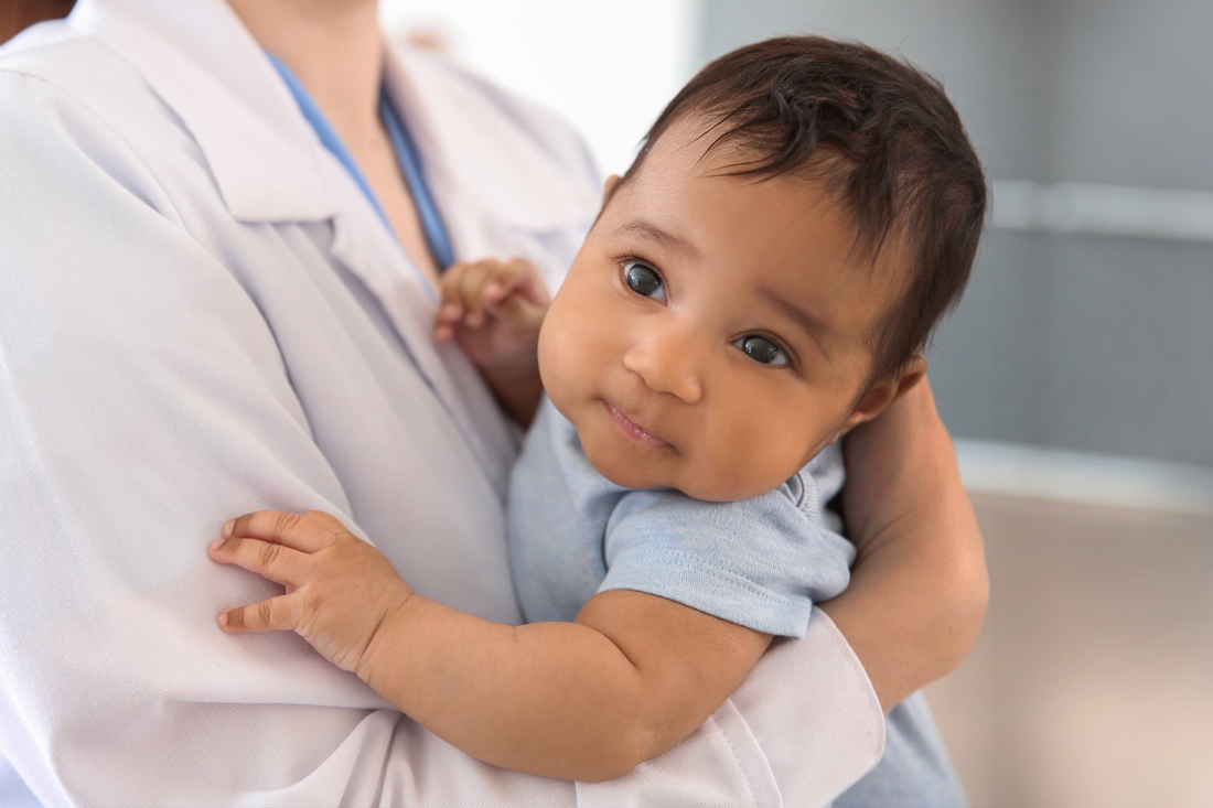 Infant looking up, in doctors arms.