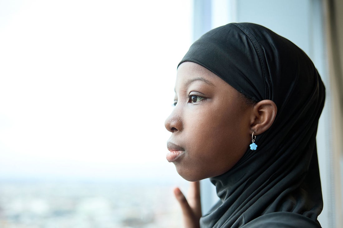 Girl with black headscarf looking out the window