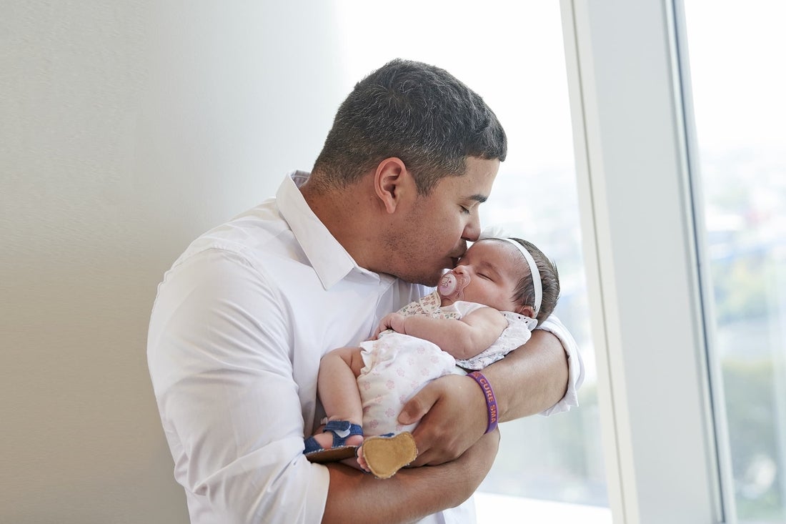 Father holding and kissing newborn daughter