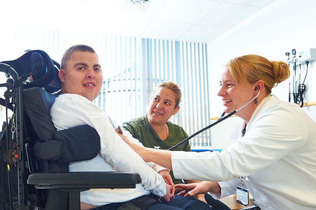 Teen boy in wheelchair getting examined by doctor.