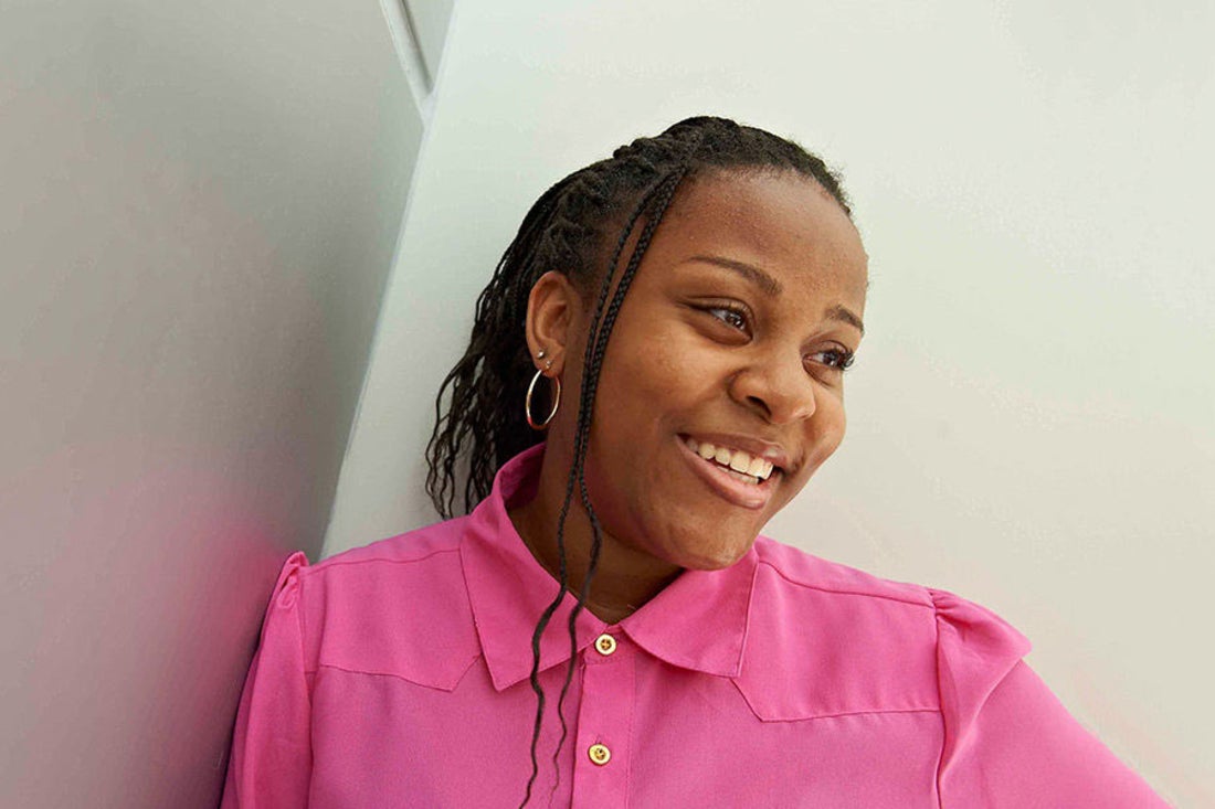 Teenage girl in bright pink shirt looking to the side and smiling.