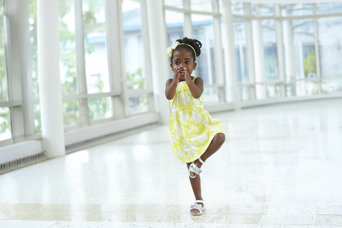 Young girl with her hands up to her face balancing on one leg