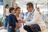 Child and mother smiling talking with medical professional