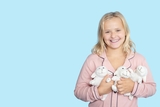 Smiling blonde girl wearing her pajamas while she holds her three plush sheep