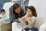 Female physician holds a cup for her female patient while she drinks it