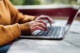 Close up of a woman typing on laptop