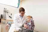 Doctor with patient using headphones to hear his heartbeat