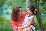 Asian girl with hearing aid laughing with her mom in the hospital garden