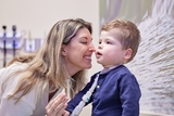 Blonde boy with tracheostomy in exam room with his mom