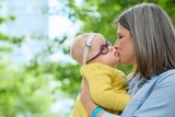 Mom kissing baby girl with yellow sweater