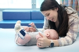 White mom smiling at baby boy while his laying down in hospital bed