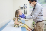 Male physician examining his young female patient.