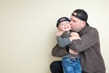 dad kissing his young son on the cheek.