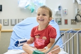 Smiling young boy wearing a red t-shirt while doing his Infusion session at the hospital.