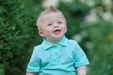 Smiling young boy with down syndrome wearing a blue polo shirt and brown shorts.