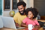 father and kid smiling at the computer.