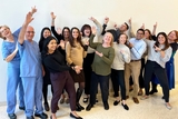 Group of physicians smiling and pointing at the ceiling.