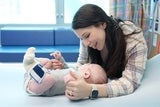 mother smiling at her baby boy in his hospital bed.